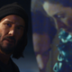 Keanu Reeves in front of a screen playing the original matrix.